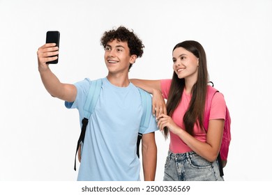 Positive high school pupils students teenagers classmates boy girl friends social media blogger in casual with bags takes selfie photo holding mobile smart phone posing on white background. - Powered by Shutterstock