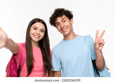 Positive high school pupils students teenagers classmates boy girl friends social media blogger in casual with bags takes selfie photo holding mobile phone doing peace victory on white background. - Powered by Shutterstock