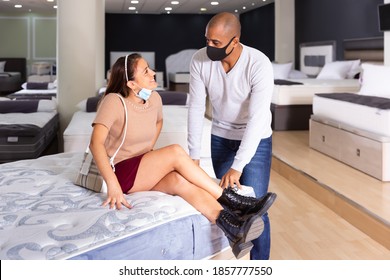 Positive Hispanic Couple Wearing Protective Face Masks Looking For New Mattress For Bed In Furniture Showroom. New Lifestyle During Coronavirus Pandemic