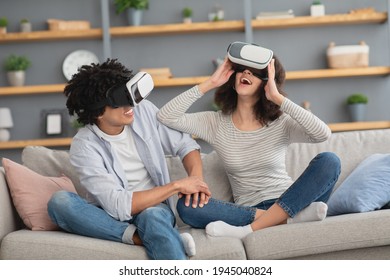 Positive Human Emotions, Online Cyber Digital Game During Covid-19 Outbreak. Amazed Smiling Millennial African American Male And Lady In Vr Glasses In Virtual World In Living Room Interior, Copy Space