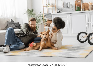 Positive interracial couple taking care of handicapped dog on floor in kitchen - Powered by Shutterstock