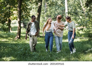 Positive interracial teenagers walking on grass in park - Powered by Shutterstock