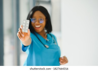 Positive Joyful Young African American Woman Pharmacist Or Doctor, Holding In Hands Pills