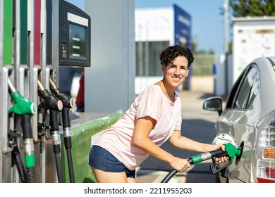 Positive Latin Woman Filling Up Tank Of Her Car With Gasoline In Gas Station