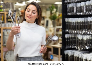 Positive latino american woman chooses flatware in the cookware section at shop