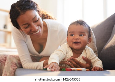 Positive loving young black mother spending beautiful time with her baby on maternity leave at home