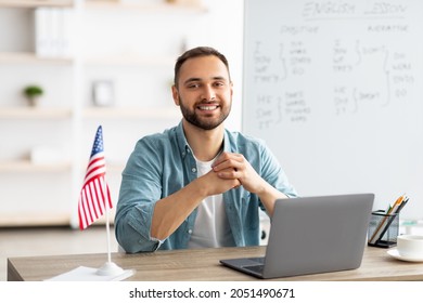 Positive male teacher giving English lesson online, using laptop at home office. Young Caucasian tutor explaining grammar rules to students on web indoors. Modern remote education concept - Powered by Shutterstock