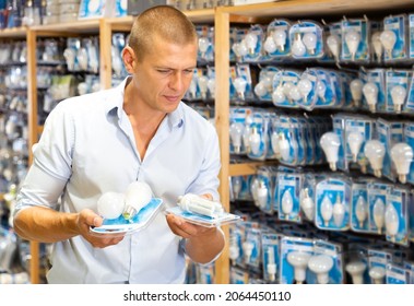 Positive man chooses new bulbs in lighting shop - Shutterstock ID 2064450110