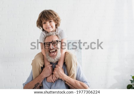 Positive man holding smiling child at home