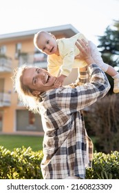 Positive Man Looking At Camera While Holding Baby Daughter On Urban Street In Treviso