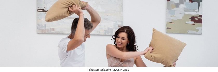 Positive Man Pillow Fighting With Brunette Wife At Home, Banner