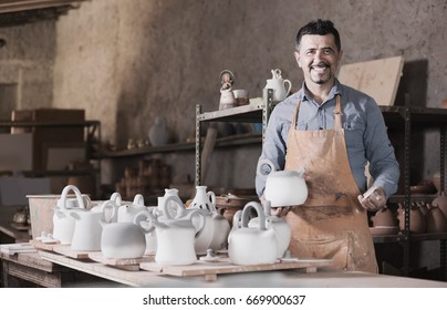 Positive Man Potter Holding Ceramic Vessels In Atelier