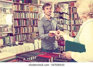 Positive Man Taking New Book From Seller In Book Store