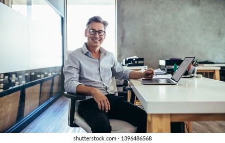 Positive Mature Businessman Sitting At Office Desk. Mid Adult Caucasian Male Executive At Work.