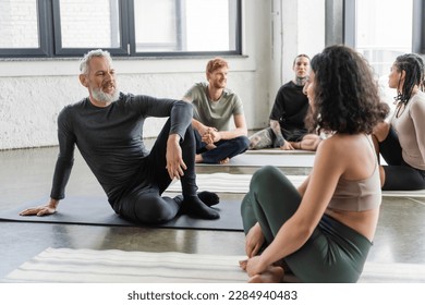 Positive mature man talking to middle eastern woman in yoga class - Powered by Shutterstock