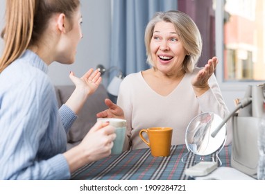 Positive mature woman having emotional conversation with her adult daughter at home