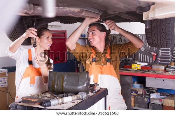 Positive mechanics crew repairing a broken car\
at garage\