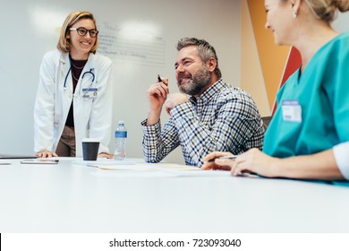 Positive Medical Team Interacting At A Meeting In Hospital Boardroom. Male And Female Healthcare Workers During A Medical Briefing.