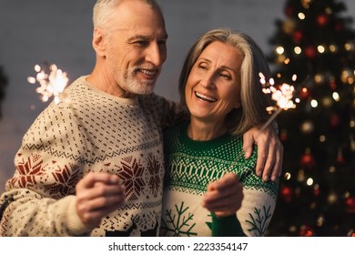 positive middle aged man hugging wife while holding sparkler on christmas eve - Powered by Shutterstock