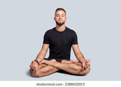 Positive millennial european man with beard in sportswear practice yoga in lotus position, enjoy breath exercises, calm, peace and health care, isolated on gray studio background - Powered by Shutterstock