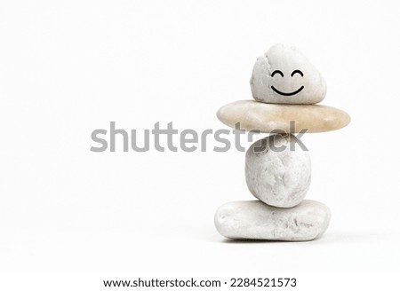 Positive Mind and  Harmony, Enjoying Life Concept, Hand Setting Natural Pebble Stone with Smiling Face Cartoon to Balance. Balancing Body, Mind, Soul and Spirit. Mental Health Practice.               