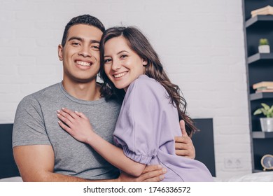 positive mixed race man and cheerful woman hugging at home - Shutterstock ID 1746336572