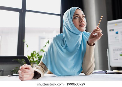 Positive Muslim Engineer Holding Pen While Thinking In Office