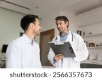 Positive optimistic Latin doctor giving consultation, recommendation to patient after checkup, talking to man in examination room, holding pad with medical records, writing notes, filling out survey