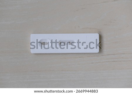 A positive ovulation test shows two lines on a wooden background. This home test kit helps women identify their most fertile days for conception planning.