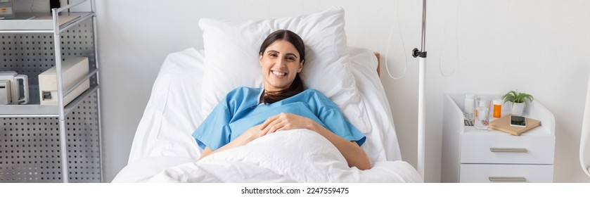 Positive patient smiling at camera on bed in hospital ward, banner - Powered by Shutterstock