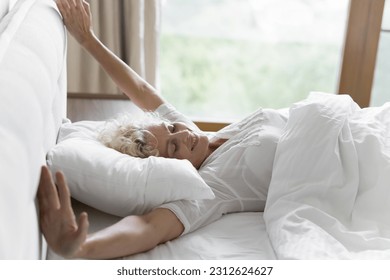 Positive peaceful pretty senior woman awaking in comfortable bed, stretching body, opening hands, lying in white bedclothes, smiling, enjoying good morning leisure on soft mattress - Powered by Shutterstock