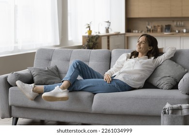 Positive peaceful young woman resting on sofa at home, leaning on back, breathing fresh air, looking at window away, enjoying break, leisure, thinking, dreaming. Full length shot - Powered by Shutterstock