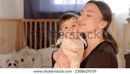 Positive physical contact between mother and baby. She holds the girl in her arms, presses to her cheek. Mental balance in parenting relationships.