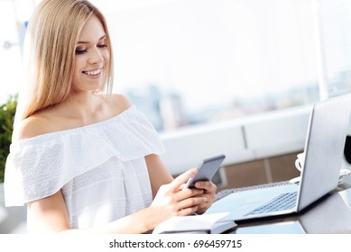 Positive pleasant woman holding her smartphone