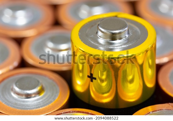 Positive polarity\
view of 1.5 V AA Alkaline batteries. Battery with yellow outer\
layer coating in selective focus. Above the yellow plated battery\
values. Differences\
concept.