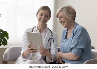 Positive practitioner doctor showing tablet screen to elder 70s patient woman, explaining checkup result, medical screening, roentgen electronic shot, giving consultation on appointment - Powered by Shutterstock