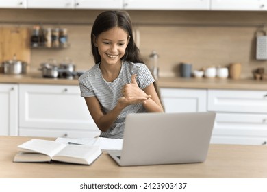 Positive pre teen schoolkid girl with hearing disability using laptop at home, studying online, talking on video conference call, using deaf language, showing hand signs at screen - Powered by Shutterstock