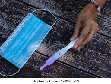 Positive Pregnancy Test On A Surgical Mask. Pregnancy During Pandemic  Woman's Hand Hold The Test And Show Positive Pregnancy, Result Done In Time Covid