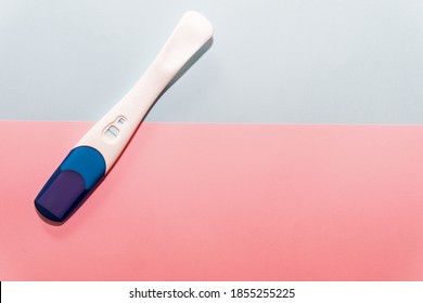Positiver Schwangerschaftstest auf blauem und rosafarbenem Hintergrund. Schwangerschaftstest. Schwangerschaftskonzept.