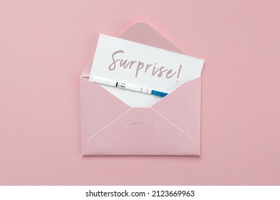 Positive Pregnancy Test In Pink Envelope On Pink Background, Postcard With Inscription Surprise, Pregnancy Concept