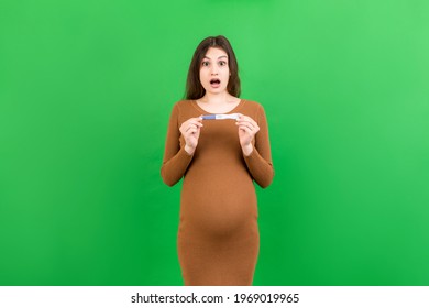 positive pregnancy test with two stripes against happy pregnant woman abdomen at Colored background. Future mother in gray dress. Pregnancy surprise. Copy space.