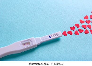 Positive pregnancy test with two strips and a hearts. Green mint background and blank space for text copy paste