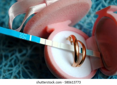 positive pregnancy test and wedding rings - Shutterstock ID 580613773