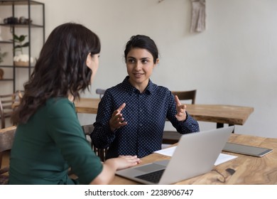 Positive pretty Indian mentor woman training intern, new employee, talking to coworker at office workplace, speaking with hands gestures, explaining task, telling about business project - Powered by Shutterstock