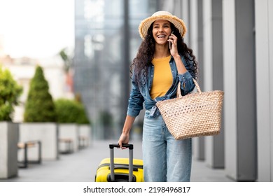 Positive Pretty Young Brunette Woman In Casual Tourist Having Phone Conversation While Walking Outside Airport, Arrived For Summer Vacation, Having Phone Conversation With Friend, Copy Space