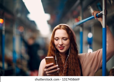 Positive Redhead Young Woman With Mobile Phone In Subway Train. Girl In Moscow Metro Subway.