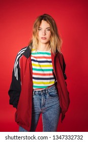 Positive Retro Styled Fashionable Woman Portrait In Sport Jacket And Jeans On Red Background. Fashion Back To 80s - 90s New Trend Concept