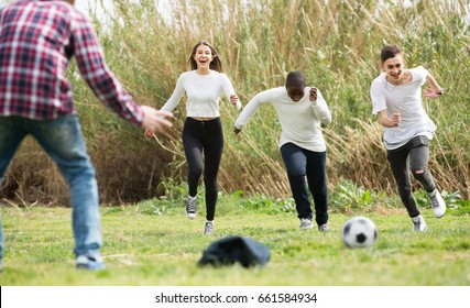 positive russian girl and three boys playing football in spring park and smiling - Shutterstock ID 661584934