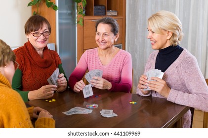 Positive russian senior female friends staking money during bridge
