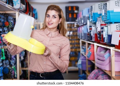 Positive Salesgirl In Pet Store Suggesting Pet Food Dispenser